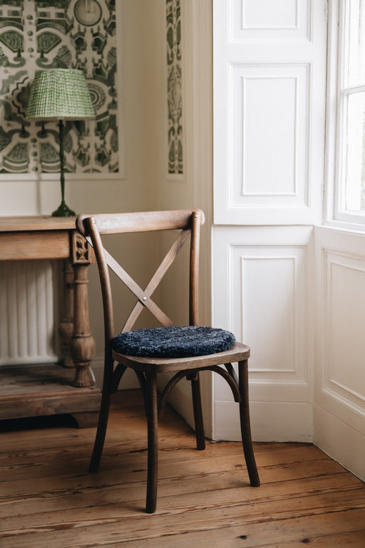 Black sheepskin round seat pad on wooden chair