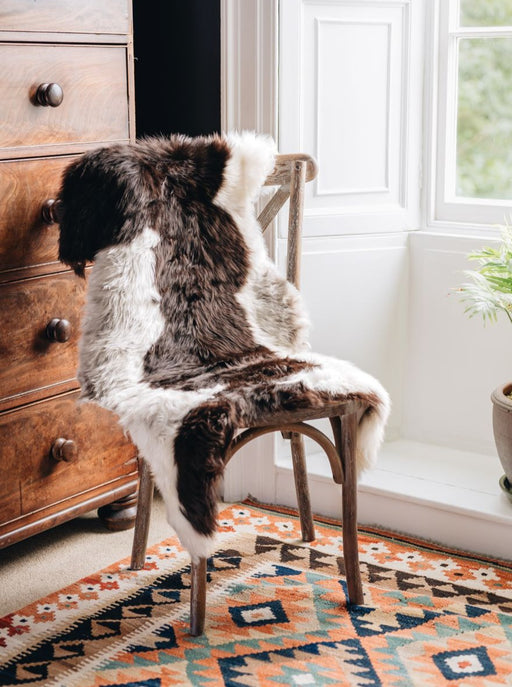 British Jacob rug in Natural white and brown spots draped over a wooden chair