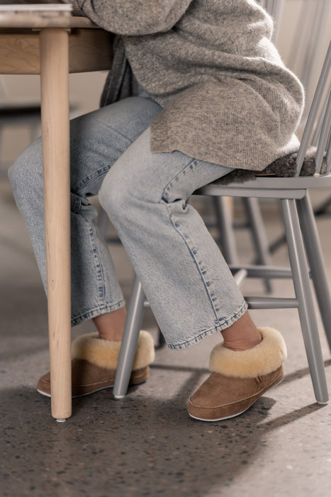 Emmy Shepherd Sheepskin Womens slipper made from Sheepskin in a chestnut colour on the foot of a model sitting down working