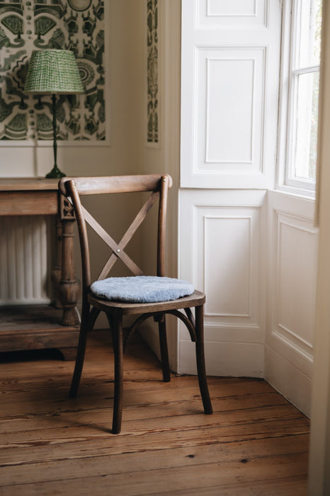 Grey sheepskin round seat pad on wooden chair