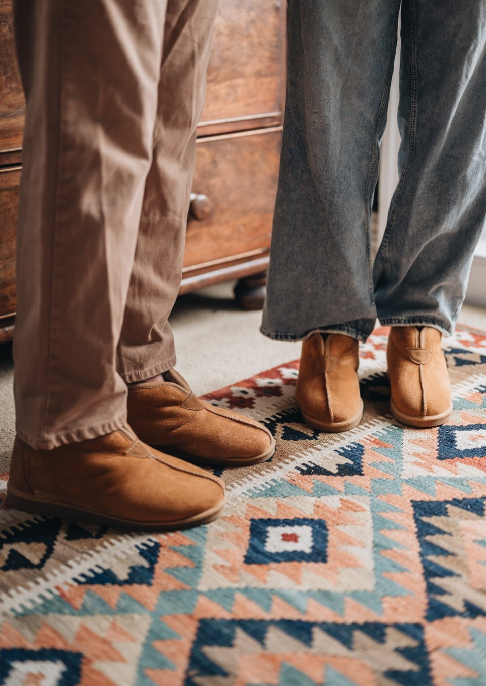 two peoples feet wearing huw and erin the unisex sheepskin slipper