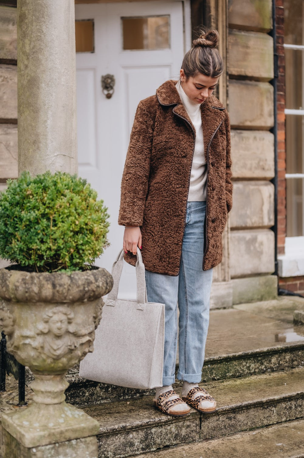 lady wearing sheepskin coat holding wool bag