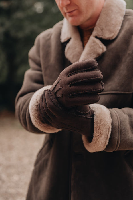 man wearing sheepskin coat with sheepskin mittens in brown