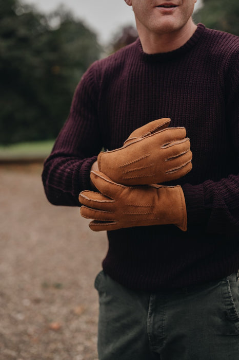 man wearing tan sheepskin gloves