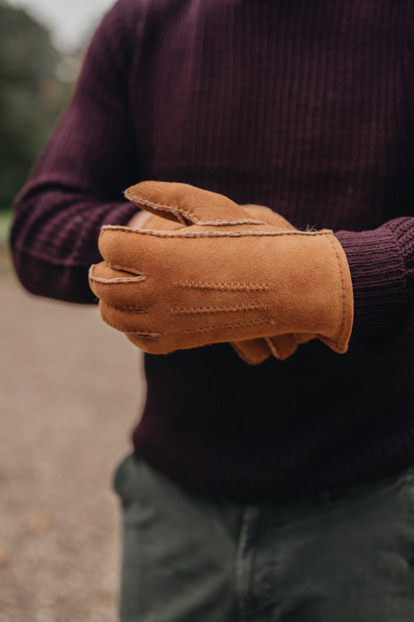 man wearing tan sheepskin gloves