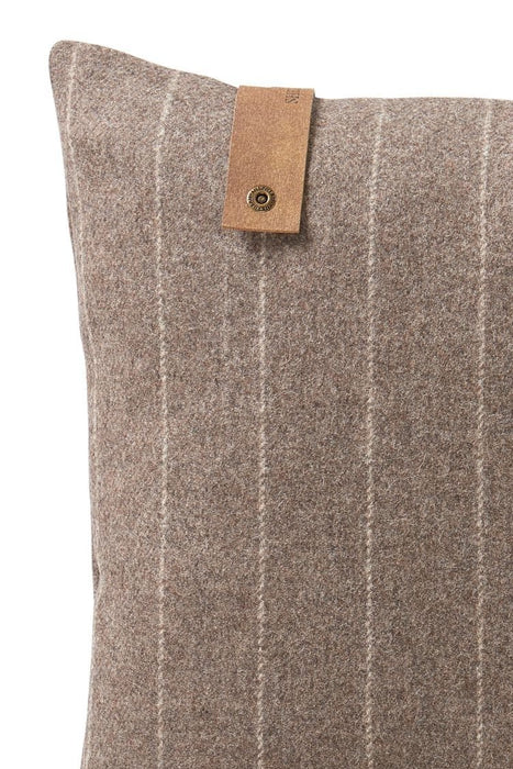 Detail of Marina Shepherd Wool Cushion in Cappuccino. A soft brown/grey cushion with crème thin stripes. Leather Shepherd branded tag attached to upper right side of cushion.