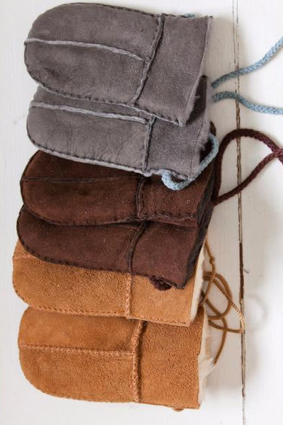 A row of baby / toddler Sheepskin Mittens in Tan, Brown and Grey. Features a string cord to stop losing them.